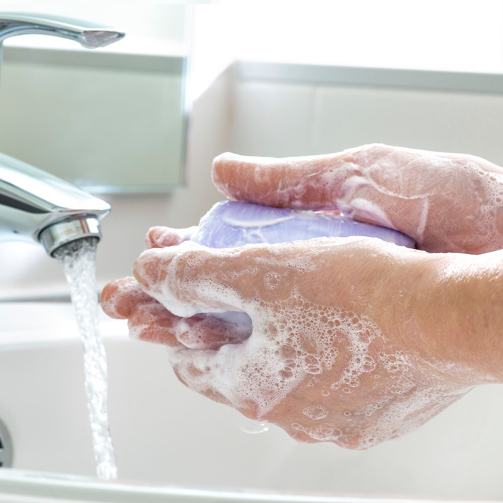 A person washing their hands in a sink with a purple bar of soap
