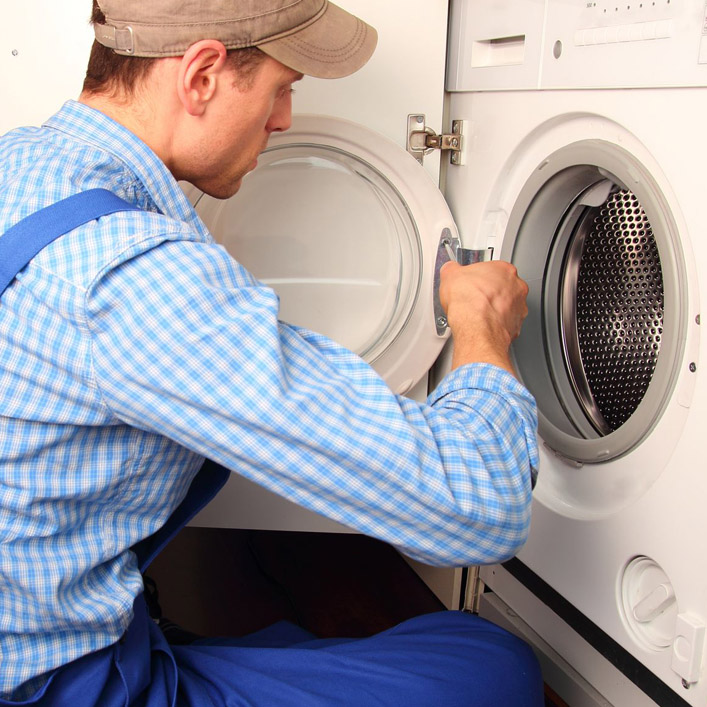 Maintenance person in a blue checkered shirt fixing the door to a washing machine